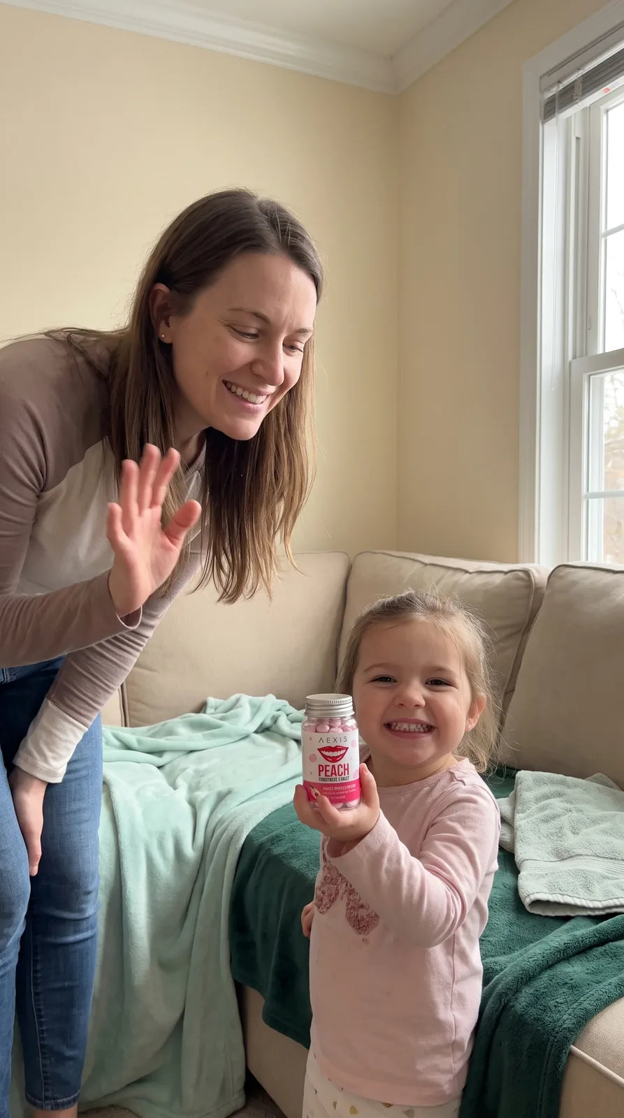A girl holds the Aexis bottle up to the camera beside her mom